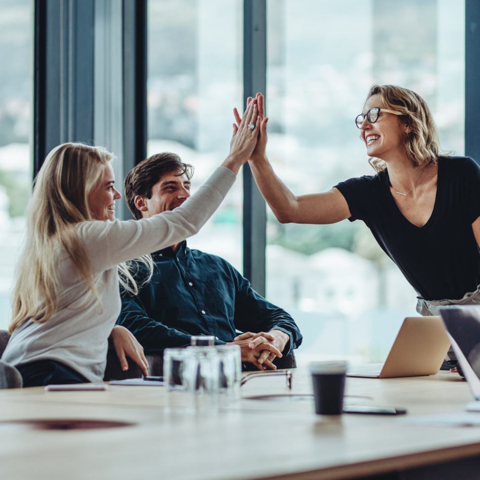 Female professional giving a high five to her colleague in conference room