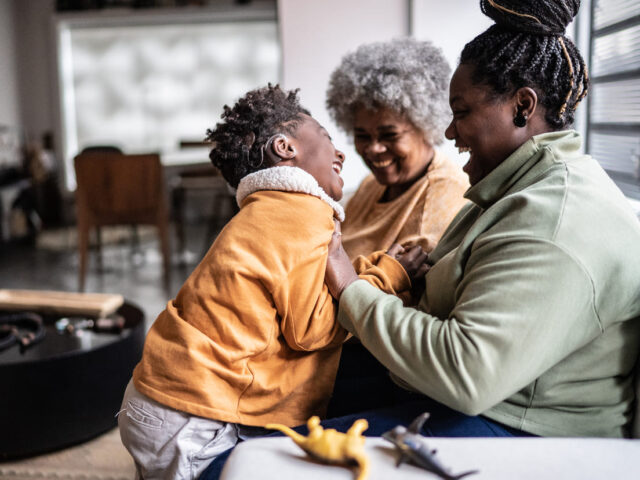 Child playing with his mother and grandmother in the living room at home