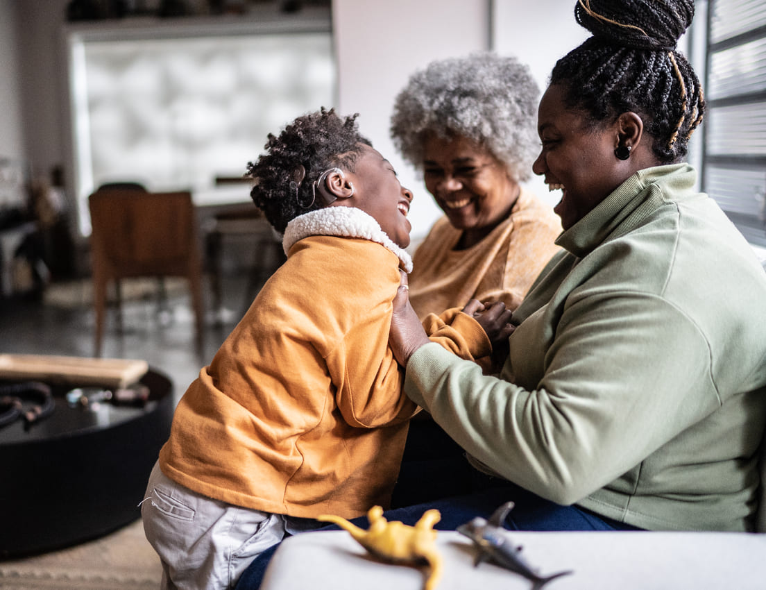Child playing with his mother and grandmother in the living room at home