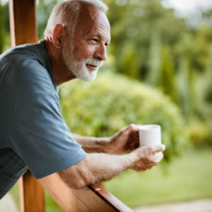 William Russell - International Income Protection - Affordable - man smiling with coffee on balcony