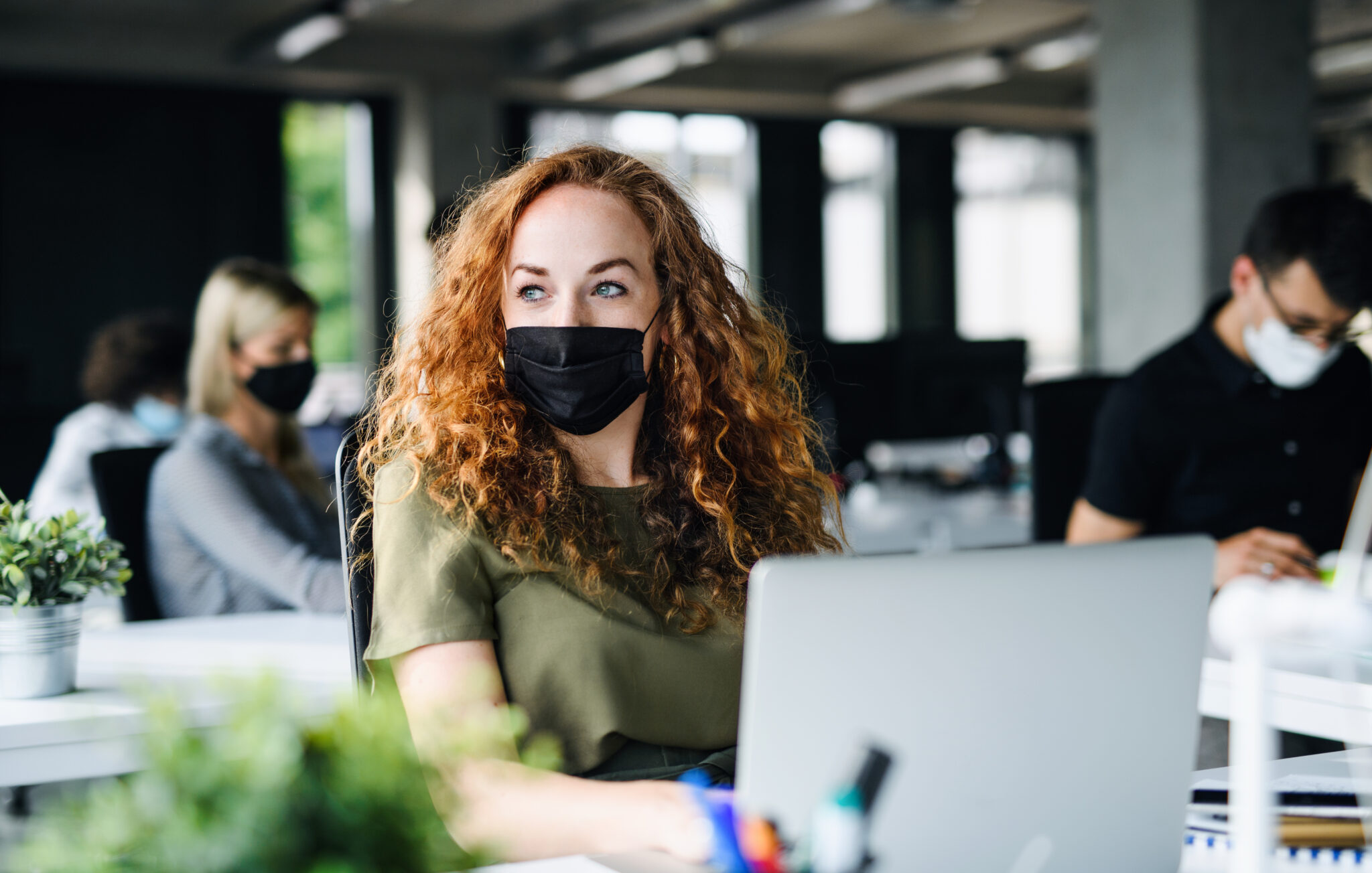 William russell blog - expat employees return to work - woman at work staring out of window with mask on