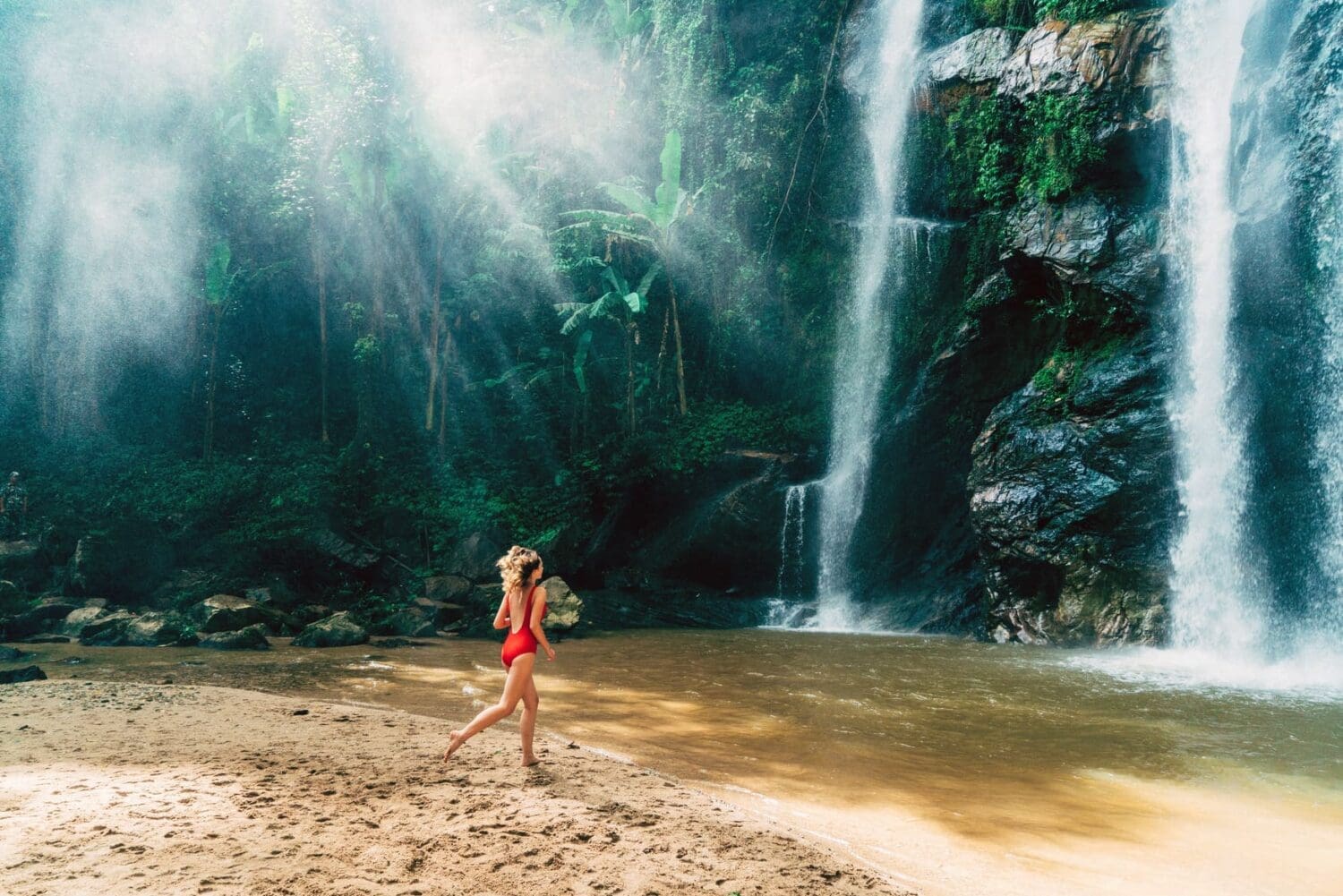 Williarm-Russell-blog-post-article-top-workation-destinations-best-to-work-from-Young-Caucasian-woman-running-to-the-tropical-waterfall -in-Thailand