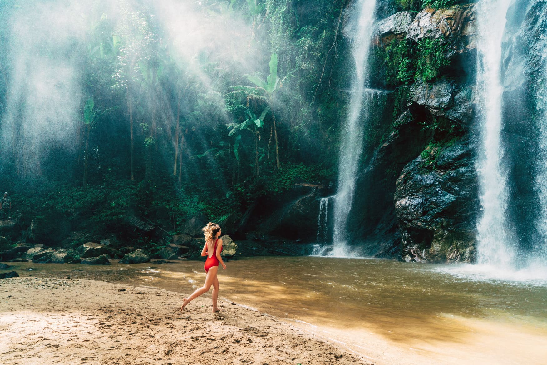 Williarm-Russell-blog-post-article-top-workation-destinations-best-to-work-from-Young-Caucasian-woman-running-to-the-tropical-waterfall -in-Thailand