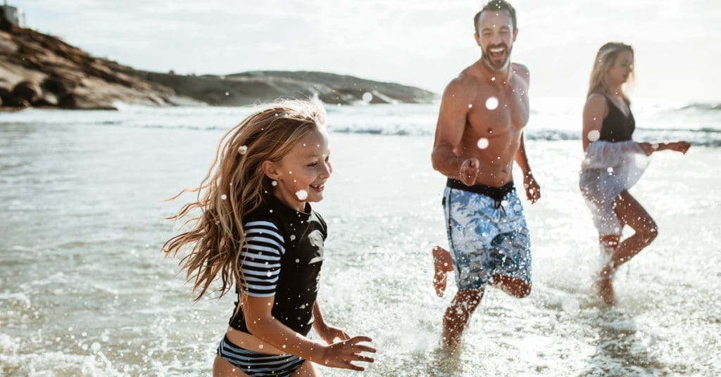 Girl with parents playing at the beach - British Expats Moving & Living Abroad: The Ultimate Guide
