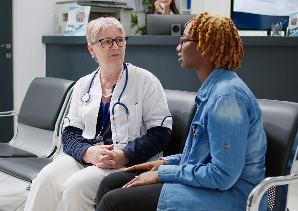 Senior physician consulting woman in waiting room lobby