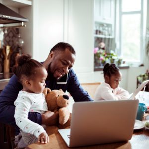 William Russell Global Life Insurance - dad holding daughter whilst on computer and phone small
