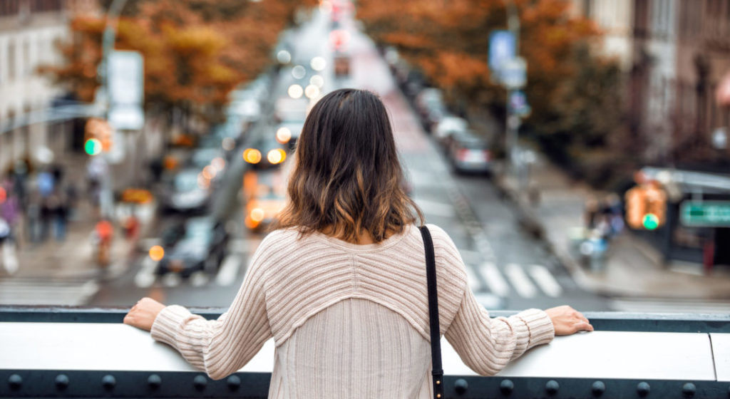 William Russell - how much does expat health insurance cost image - woman in new york on balcony looking out