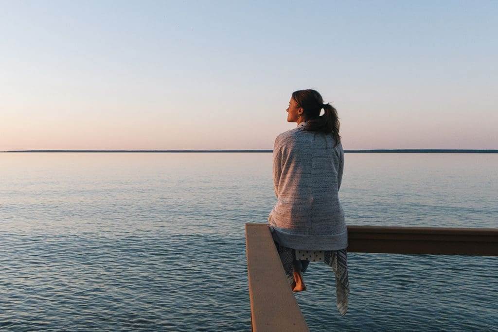 William Russell - Blog - Top Tips for Good Mental Health Depression as an Expat - Young woman sitting on edge looks out at view