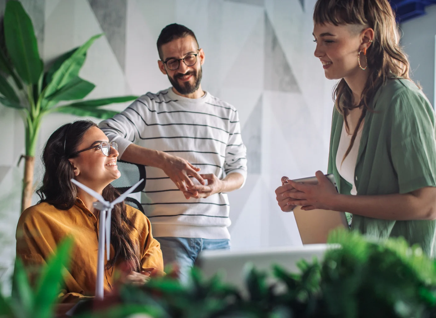 Team members engaged in a discussion in a modern office surrounded by plants
