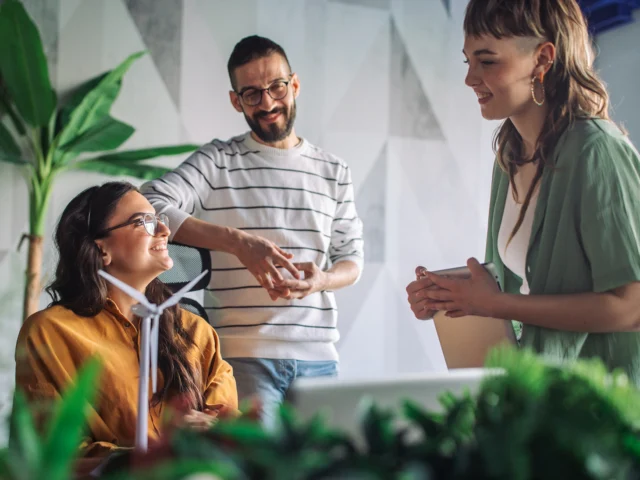 Team members engaged in a discussion in a modern office surrounded by plants